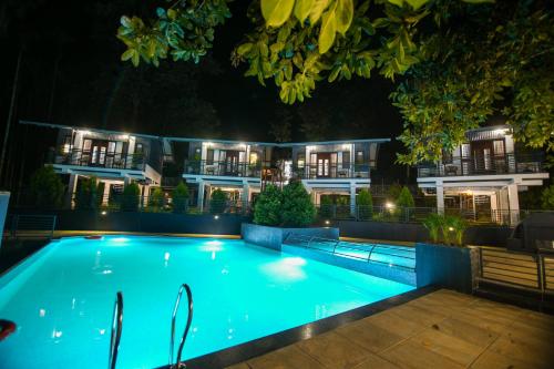 瓦亚纳德B'camp Resorts & Homestays的一座游泳池,在晚上在建筑物前