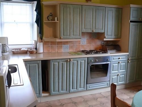 CovingtonThe Gardener's House的厨房配有绿色橱柜和炉灶。