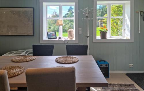 法尔松4 Bedroom Amazing Home In Farsund的一间带木桌和2扇窗户的用餐室