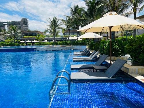 芽庄Luxury villa trong Whyndham garden Cam Ranh的一个带躺椅和遮阳伞的游泳池