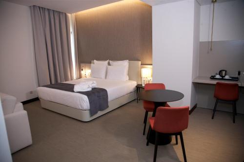 罗安达Hotel Continental Horizonte的酒店客房带一张床、一张桌子和椅子