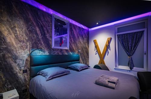 勒米尔蒙spa de la quarterelle LOVE ROOM 88 VOSGES的一间卧室配有一张紫色照明的大床