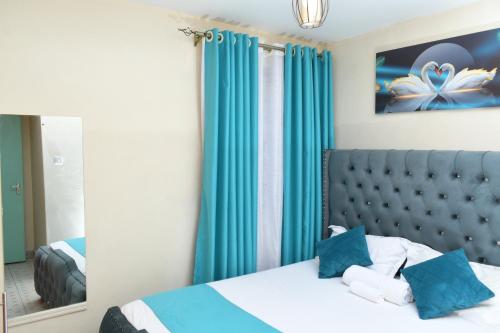 内罗毕Nomads Luxurious Homes的一间卧室配有一张带蓝色窗帘和镜子的床