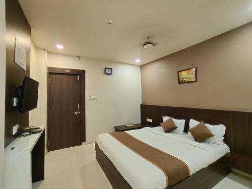 艾哈迈达巴德Hotel Palav Palace的一间卧室配有一张大床和电视