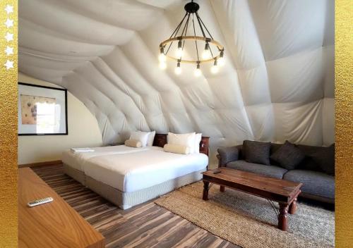 拉斯阿尔卡麦Desert Breeze Cocoon的一间卧室配有一张床、一张沙发和一个吊灯。