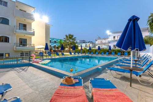 伊利索斯Anixis Hotel & Apartments的一座带椅子和遮阳伞的游泳池位于一座建筑旁边