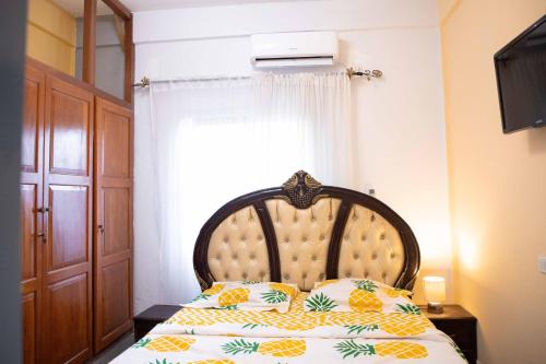 雅温得Hypo Guest Lounge的一间卧室配有一张带木制床头板的床和窗户。