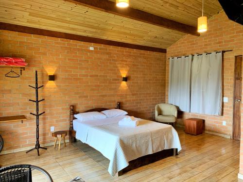 圣本图-杜萨普卡伊Chalés Canto da Serra的一间卧室设有一张床和砖墙