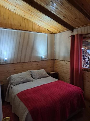 普尤瓦比港Cabañas Robinson的一间卧室配有一张带红色毯子的床
