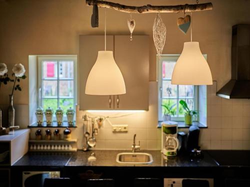 艾斯登Located 10km from Maastricht towards the Belgium border的厨房配有2盏吊灯和水槽