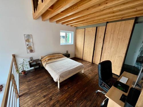 拉卢维耶尔Capstay La Louvière的一间卧室配有一张床、木地板和一张书桌