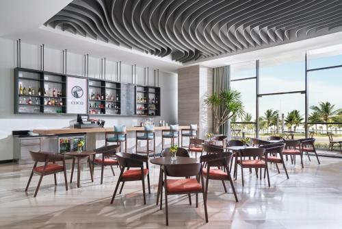 岘港voco Ma Belle Danang, an IHG Hotel的一间带桌椅的餐厅和一间酒吧
