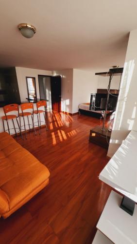 波哥大Oporto 83的客厅铺有木地板,配有橙色椅子。