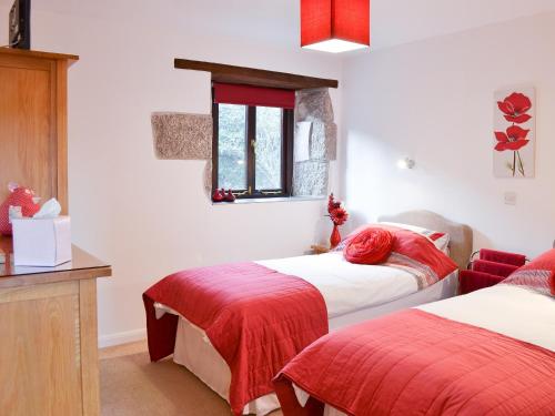 CuryLittle Content Farm Cottage的一间卧室设有两张带红色床单的床和窗户。