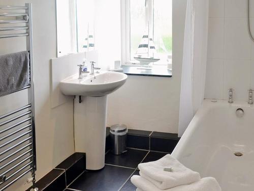 Crowan燕子谷仓乡村别墅的白色的浴室设有水槽和浴缸。