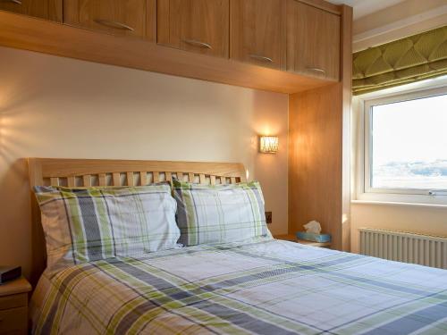 波特马多克Estuary View的一间卧室配有一张带铺着地毯的床和窗户。