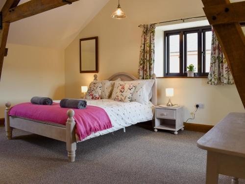 NorthleighBucknole Farm - The Old Shippon的一间卧室配有一张带粉色毯子的床