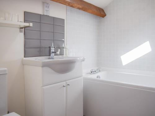 TalleyBarn Cottage的白色的浴室设有水槽和浴缸。
