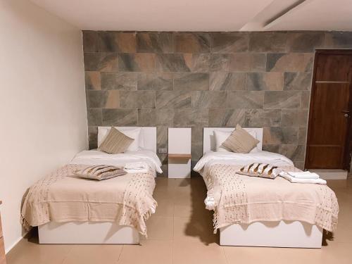 阿克拉Sky Suites East Legon的一间设有两张床和石墙的房间
