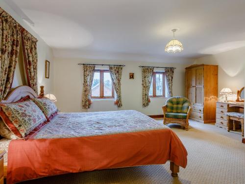 Runcton Holme普尔林巴恩度假屋的一间卧室配有一张床、一把椅子和窗户。