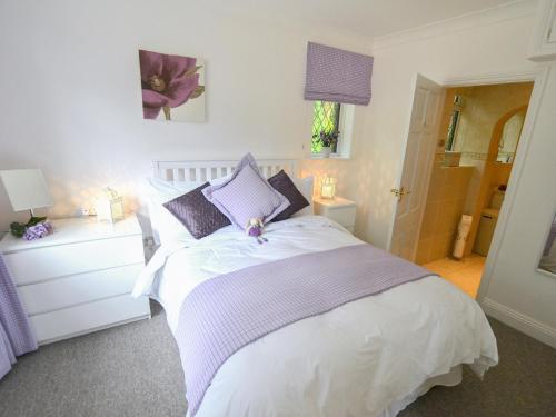 灵伍德Alices Lodge的卧室配有白色床和紫色枕头
