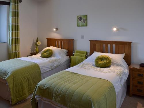 CuryEglos Derry Farm Cottage - E4597的一间卧室配有两张带绿床单和枕头的床。