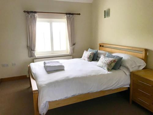 DunstallBrankley Cottage - E4712的一间卧室配有一张带白色床单的床和一扇窗户。