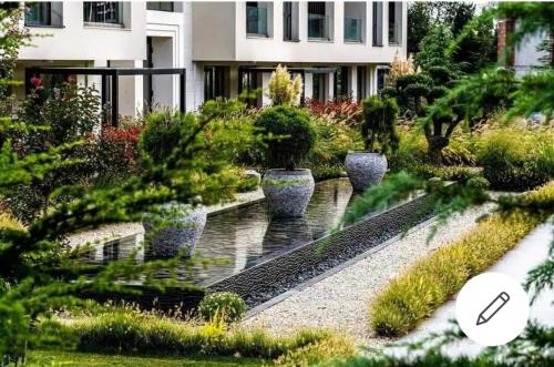 圣君士坦丁和海伦那ALLURE VARNA studios的一座花园,在一座建筑前方有一个喷泉和植物