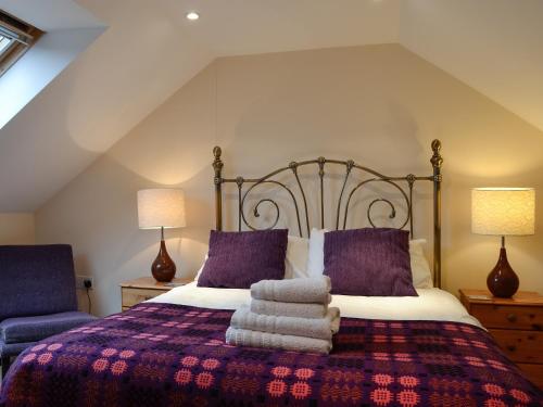 罗西里The Old Byre的一间卧室配有一张带紫色枕头的大床