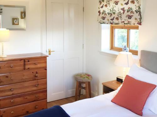 MuthillThe Wee House的一间卧室配有一张床、一个梳妆台和一扇窗户。