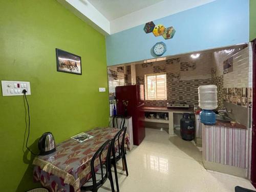 阿加尔塔拉Veda Homestay的带绿色墙壁和桌椅的厨房