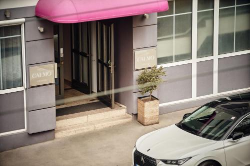 维也纳Hotel Calmo的停在大楼外的带粉红色遮篷的汽车