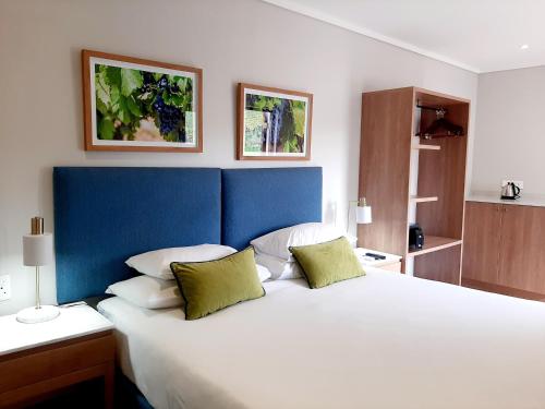 斯泰伦博斯De Zalze Lodge的卧室配有带绿色枕头的大型白色床