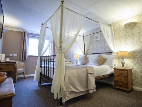 莱顿巴泽德The Heath Inn的一间卧室配有一张带一张婴儿床的天蓬床