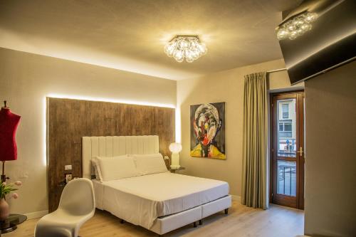 布雷西亚Hotel Battisti 31的一间卧室配有一张床、一把椅子和一个吊灯。