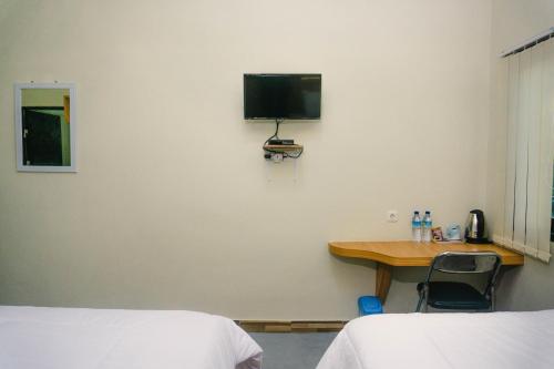 大松巴哇GRAND KHALIFAH Guesthouse的客房设有两张床和一张桌子,墙上配有电视