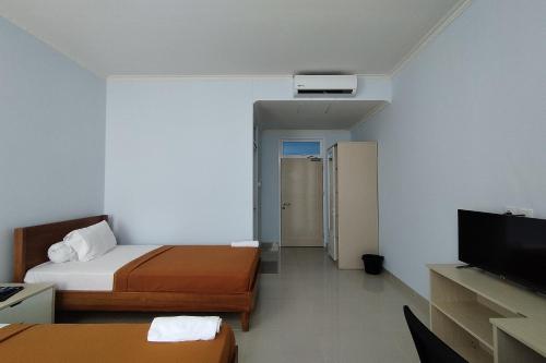 占碑市Hotel Sutha Inn的酒店客房设有两张床和一台平面电视。