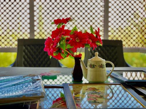 古尔马尔格Everest Guest House的花瓶,花朵红色,坐在桌子上