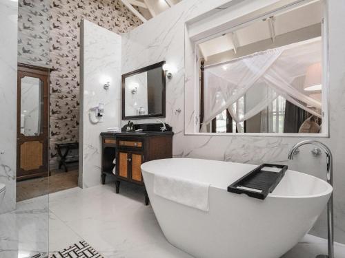 KingsmeadThe Peech Boutique Hotel Zimbabwe的白色的浴室设有浴缸和镜子