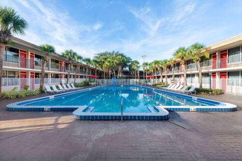 奥兰多Ramada by Wyndham Kissimmee Gateway - Free Theme Park Shuttle的棕榈树建筑前的游泳池