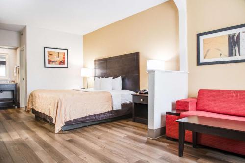 艾肯艾肯品质套房酒店的酒店客房,配有一张床和一张红色的沙发