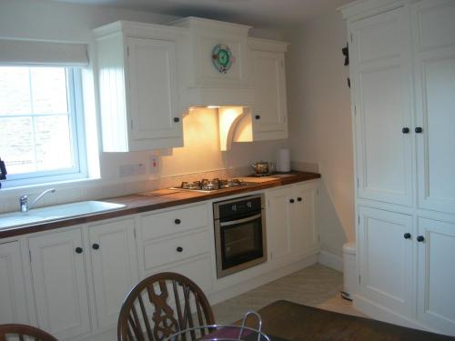 Campsey坦普尔莫伊尔农场度假屋的厨房配有白色橱柜和水槽