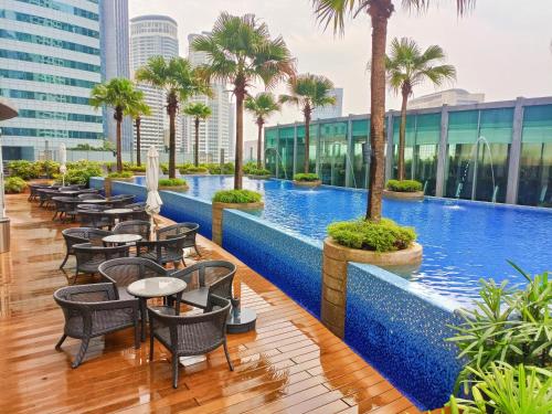 吉隆坡Vortex suites near by KLCC的酒店游泳池设有桌椅,并种植了棕榈树。