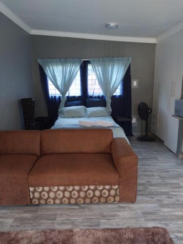 比勒陀利亚Protea guest house的一间卧室配有沙发和一张带窗帘的床