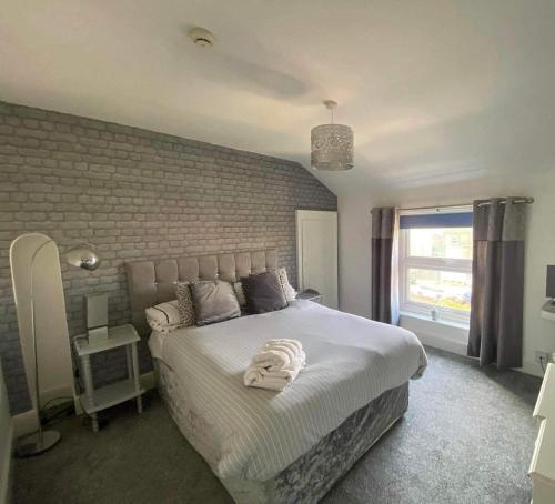 洛斯托夫特The Beach House的卧室配有一张白色大床和砖墙