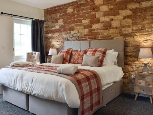PlumblandHolmegarth的一间卧室设有一张带砖墙的大床