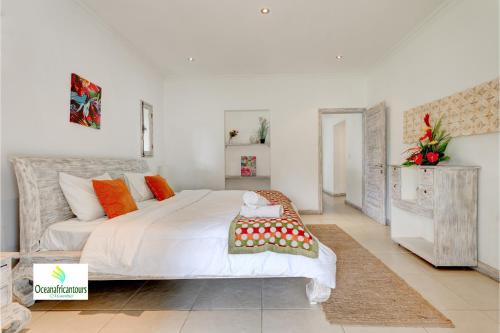格兰贝伊Oasis 1 Villa Tropicale的一间卧室配有一张橙色色调的大型白色床。