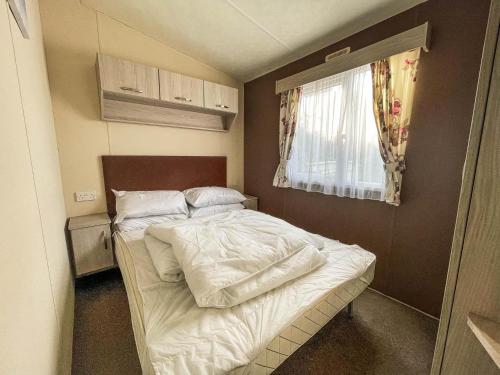 大雅茅斯Superb 8 Berth Caravan For Hire At A Great Holiday Park In Norfolk Ref 50026m的一个小房间的小床,设有窗户