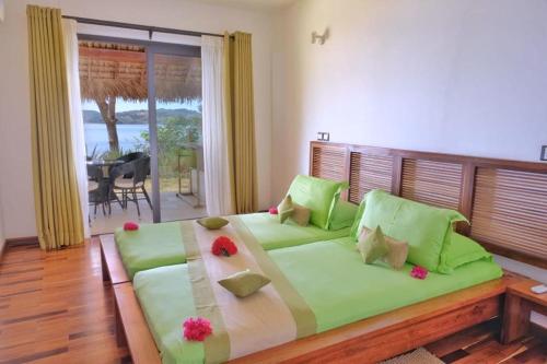 贝岛ANJARA LODGE Villa de 3 chambres的一间卧室配有一张带鲜花的大型绿色床。