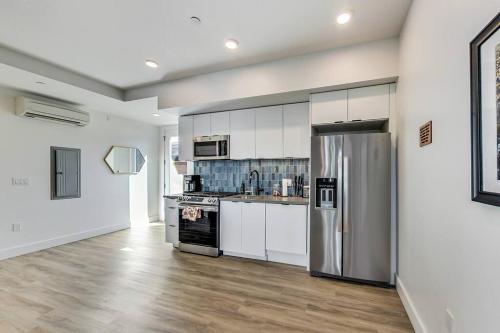 奥克兰Brand New Luxury Fully Furnished Studio Suite的厨房配有白色橱柜和不锈钢冰箱